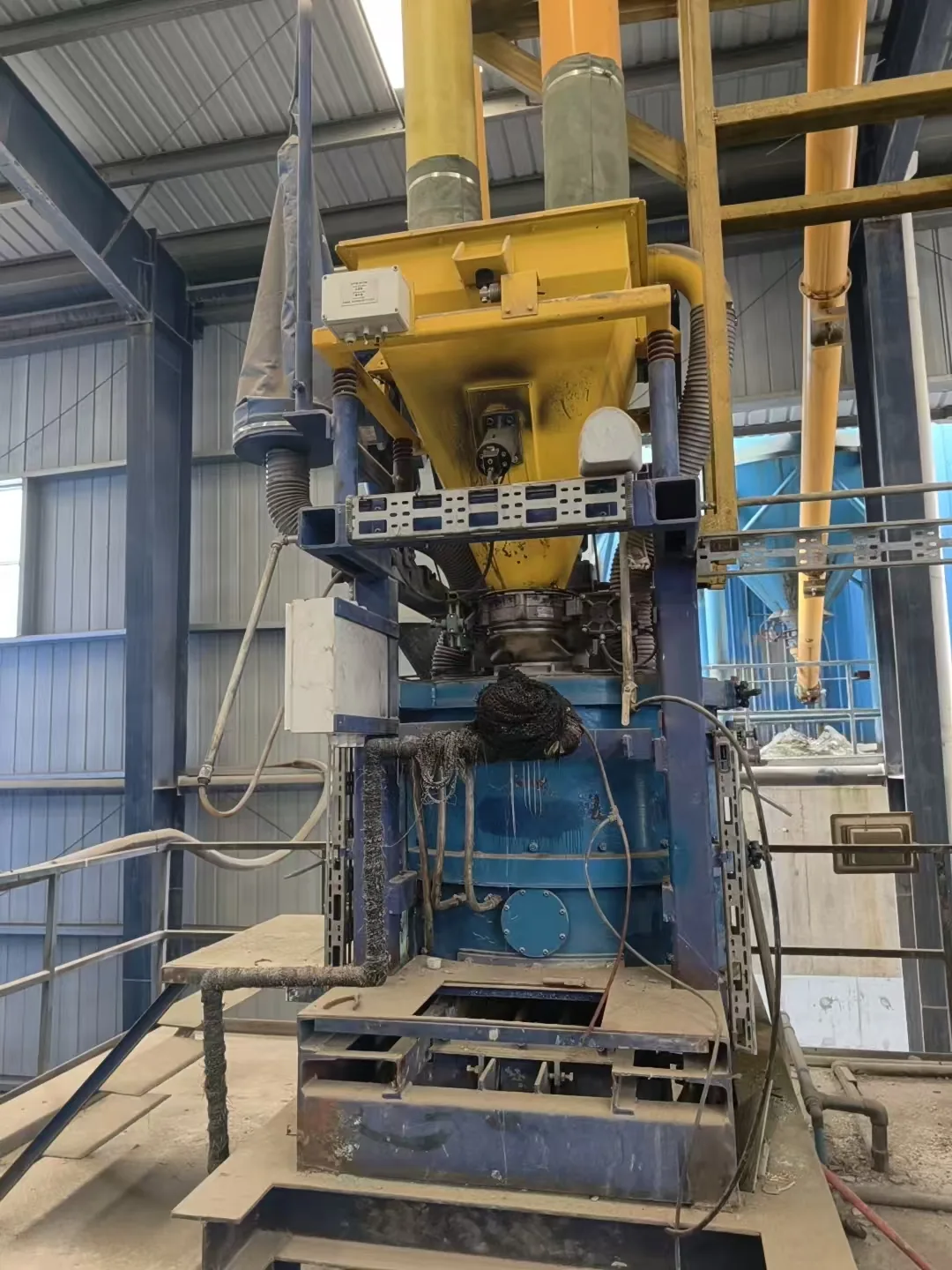 Equipment from the MASA photo library showing a yellow hopper above a blue housing inside a workshop